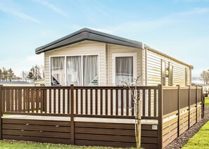 A mobile home with a fenced deck, large windows, and a 'For Sale' sign. - Two bedroom, spacious caravan. (Alyth, Perthshire)