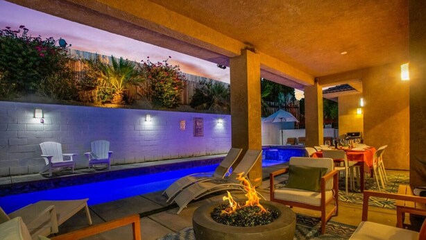A poolside area with lounge chairs, a fire pit, and a dining setup. - The Desert Gem Pool Spa Gated Private Home (Desert Hot Springs)