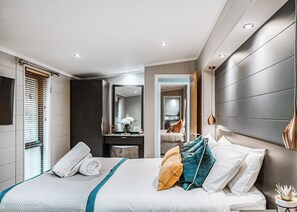 A modern hotel room with a large bed, a bedside table, a mirror, and a view into the adjacent room. - 2 bedroom accommodation in Bridgnorth (Bridgnorth)