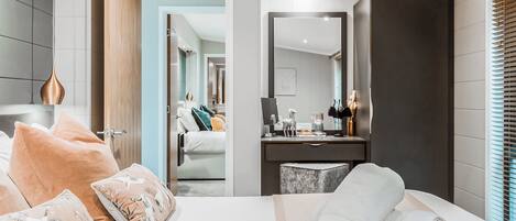 Habitación de hotel moderna con una cama grande, una mesita de noche, un espejo y vistas a la habitación contigua.