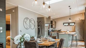A modern kitchen with a central island, pendant lighting, and a dining area with a wooden table and chairs.