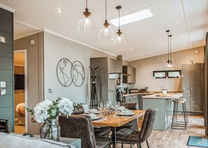 A modern kitchen with a central island, pendant lighting, and a dining area with a wooden table and chairs. - 2 bedroom accommodation in Bridgnorth (Bridgnorth)