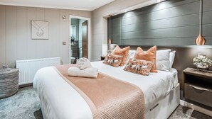 Een moderne slaapkamer met een groot bed, een nachtkastje, een radiator en uitzicht op de badkamer.