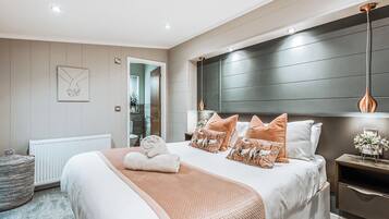 A modern bedroom with a large bed, a bedside table, a radiator, and a view into the bathroom.