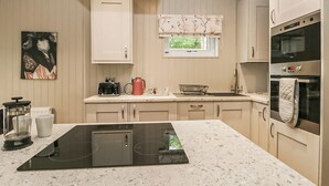 A modern kitchen with a central island, built-in oven, and a window with a view.