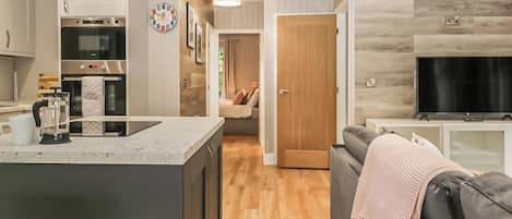 A modern kitchen with built-in appliances, a dining area with a sofa, and a TV.