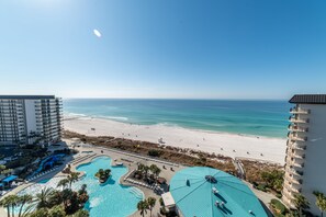 Ein Resort mit Blick auf den Strand, einem Poolbereich und einem Hochhaus.
