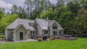 Ein zweistöckiges Haus mit überdachter Veranda, einer einladenden Eingangsterrasse und einem großen Garten.