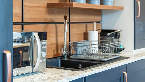 A modern kitchen with a built-in dishwasher, a stainless steel sink, and wooden cabinets.