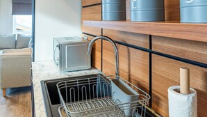 A modern kitchen with a built-in dishwasher, a toaster, and wooden shelves with storage containers.