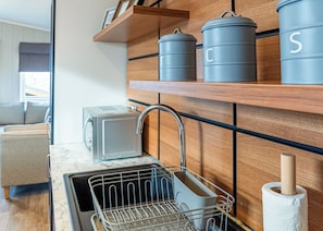 Una cocina moderna con lavavajillas incorporado, tostadora y estanterías de madera con recipientes de almacenamiento.