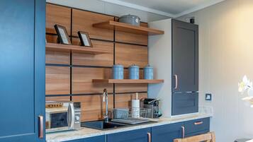 A modern kitchen with blue cabinets, a built-in oven, a sink, and a refrigerator.