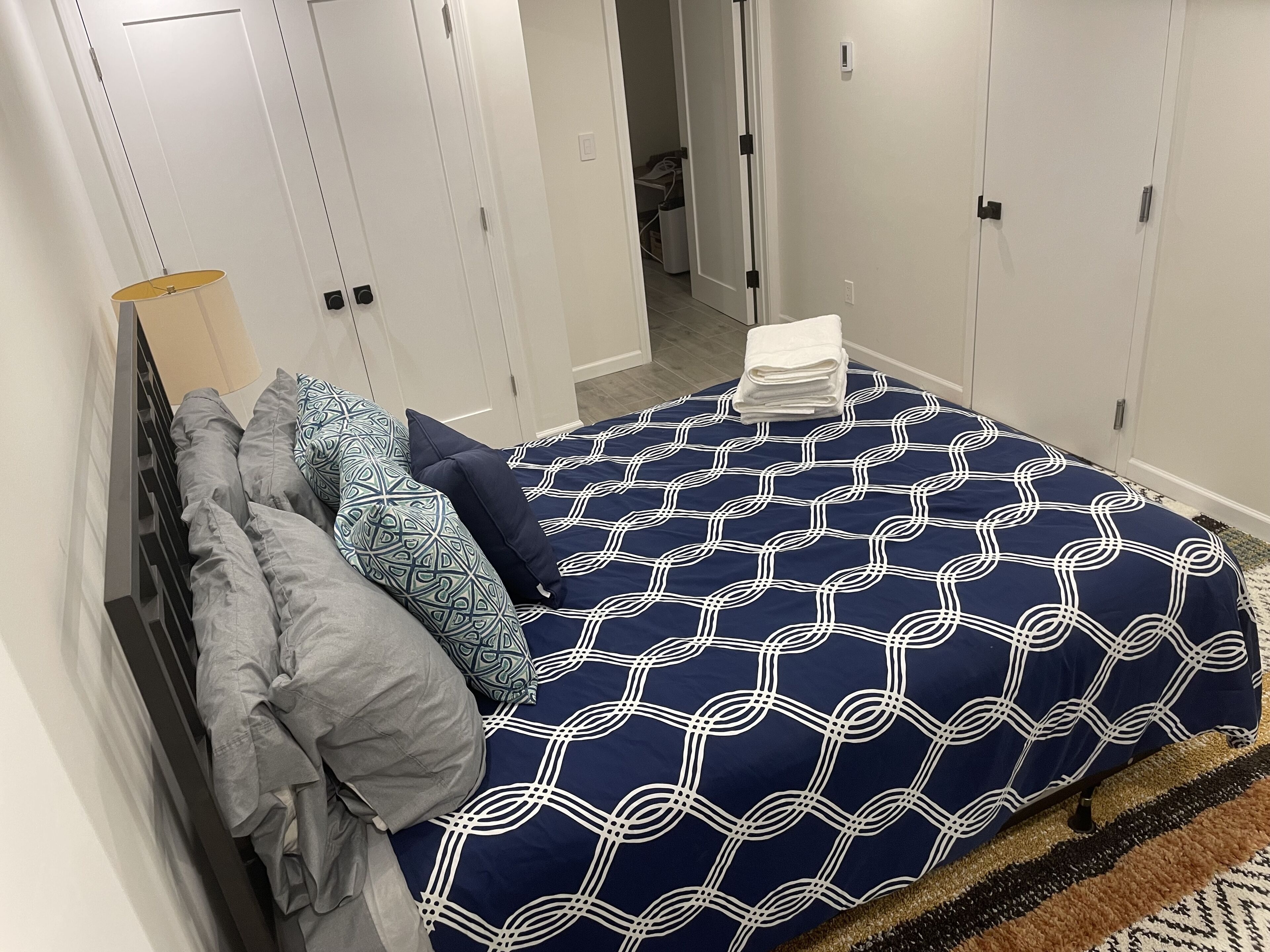 A bedroom with a bed, pillows, a lamp, and a wardrobe.