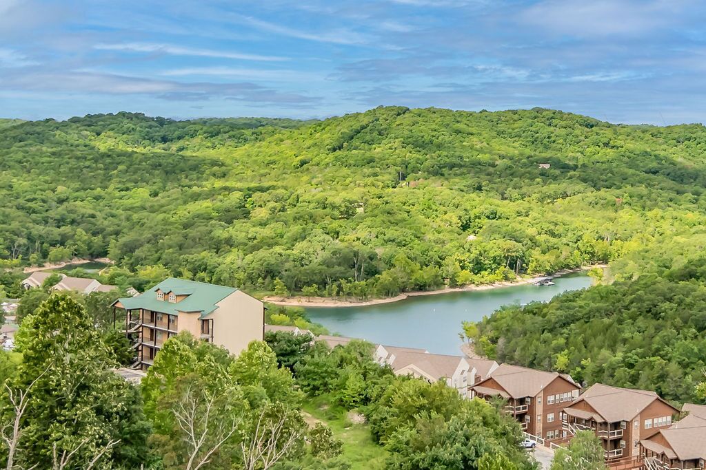 Un resort con varias edificaciones, un lago y exuberante vegetación.