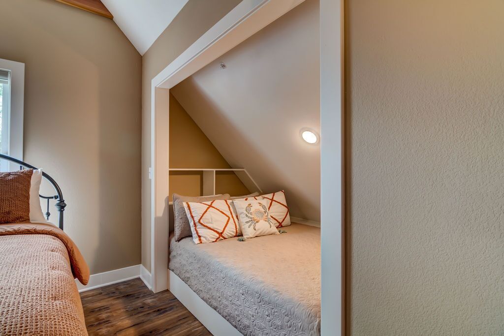 Un dormitorio con techo inclinado, una cama con ropa de cama estampada y un ventanal.