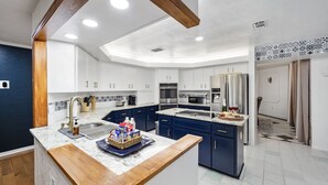 Een moderne keuken met witte kasten, een houten aanrechtblad en een ingebouwde oven.