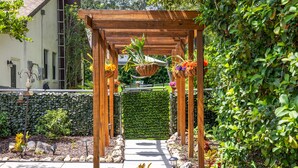 Een houten pergola met bloembakken vol bloemen in een tuin.