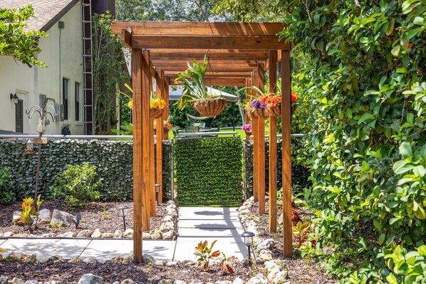 Une pergola en bois ornée de jardinières suspendues, située dans un espace jardin.
