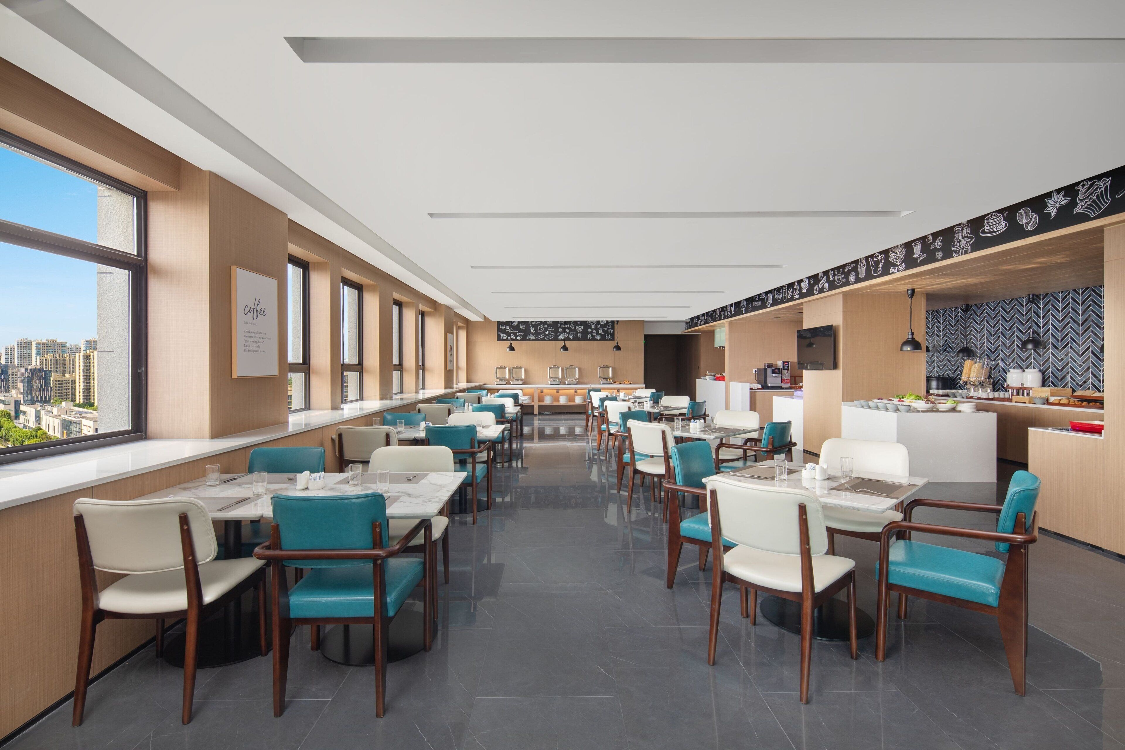 A modern hotel lobby with a long counter, seating area, and a view of the city.