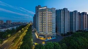 Un hotel de gran altura con varias plantas, un letrero llamativo en la parte superior y una fachada bien iluminada.