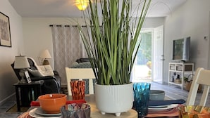 A dining area with a wooden table set for a meal, surrounded by colorful placemats, a potted plant, and various glassware. - Family Welcome-Large Comfy Stay Pets Welcome w/Parking Trailers/Bikes/Boats (Edgewater)
