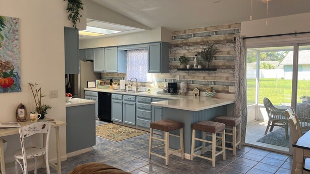 A modern kitchen with a large island, bar stools, and a dining area with a table and chairs. - Family Welcome-Large Comfy Stay Pets Welcome w/Parking Trailers/Bikes/Boats (Edgewater)