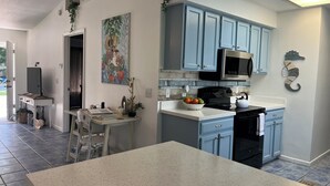 A kitchen with blue cabinets, a microwave, and a stove. There is a painting on the wall and a plant on the counter. - Family Welcome-Large Comfy Stay Pets Welcome w/Parking Trailers/Bikes/Boats (Edgewater)