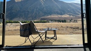 A room with a view of a mountain, a folding chair, and a small table with two cups. - Manuka Vista | under the stars getaway in Twizel (Mackenzie District)