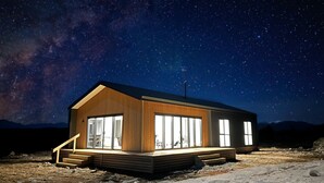 A modern cabin with large windows, a wooden exterior, and a starry night sky. - Manuka Vista | under the stars getaway in Twizel (Mackenzie District)