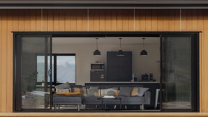 A modern interior with a large sliding glass door leading to a living area with a sofa, coffee table, and pendant lights. - Manuka Vista | under the stars getaway in Twizel (Mackenzie District)