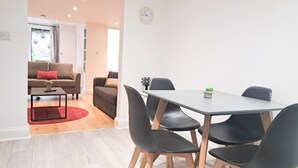Uma sala de estar moderna com um sofá, uma mesa de jantar com cadeiras e um tapete vermelho.