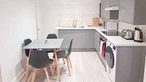 Uma cozinha compacta com área de jantar, máquina de lavar e micro-ondas.
