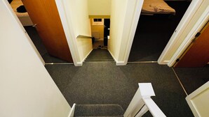 Una escalera estrecha conduce a un dormitorio con cama y ventana.