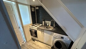 A compact kitchen with a stove, sink, and washing machine.