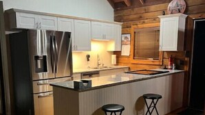 Een moderne keuken met houten balken, roestvrijstalen apparatuur en een centraal kookeiland met krukken.
