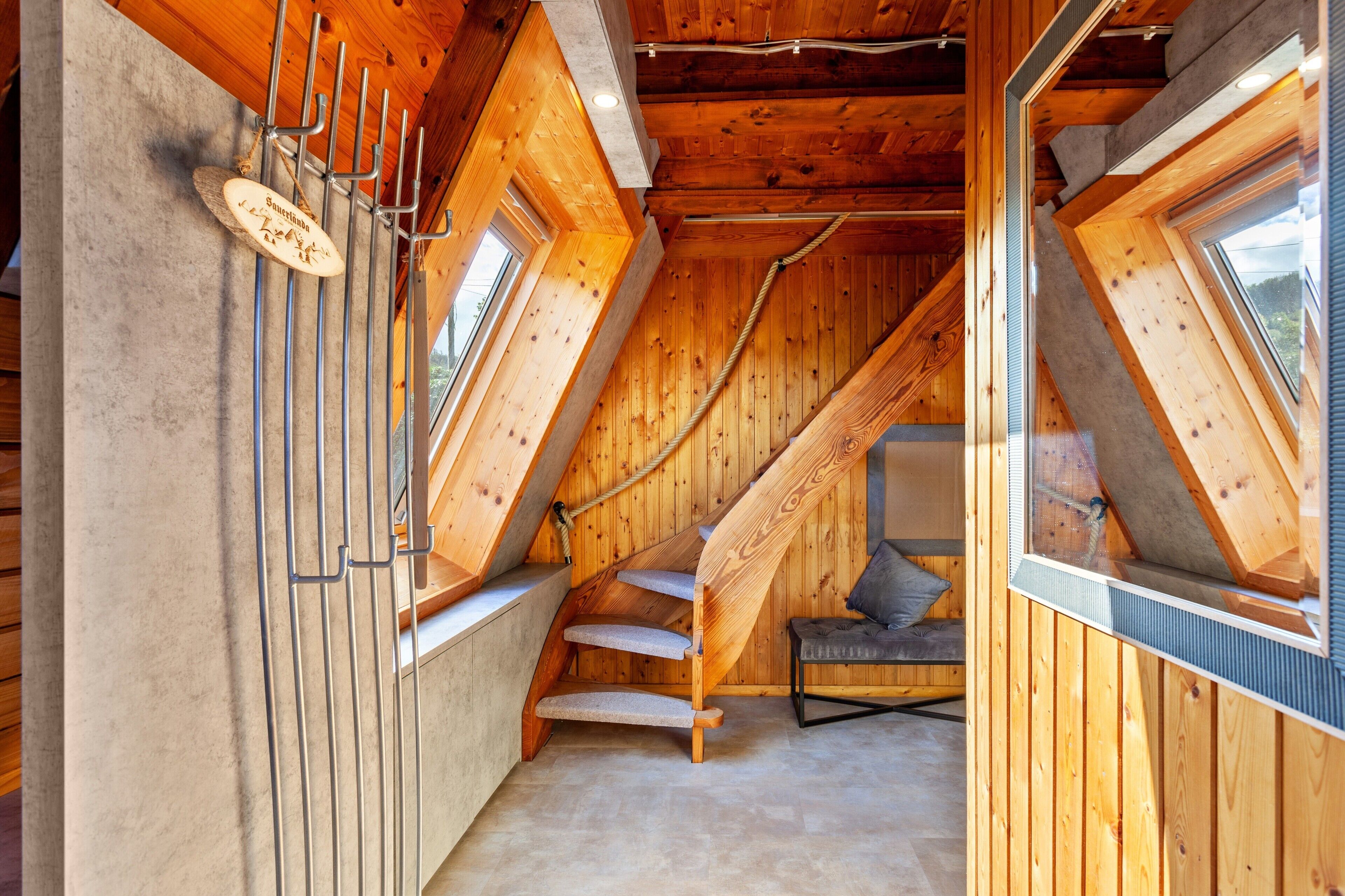 A wooden interior with a sloped ceiling, a staircase, and a window.