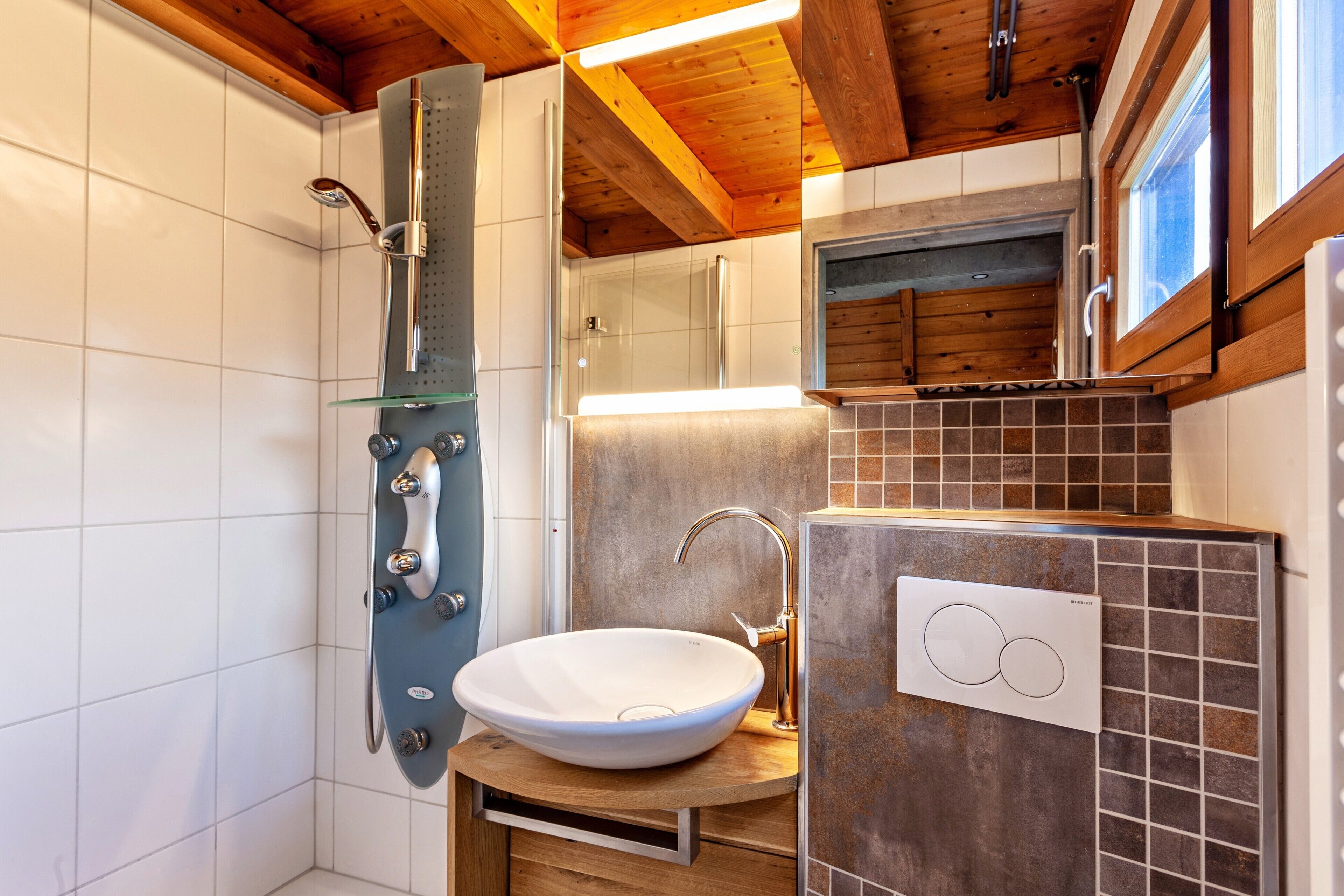 Un bagno moderno con doccia vetrata, lavandino bianco e mobile contenitore rivestito di piastrelle.