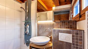 Un bagno moderno con doccia vetrata, lavandino bianco e mobile contenitore rivestito di piastrelle.