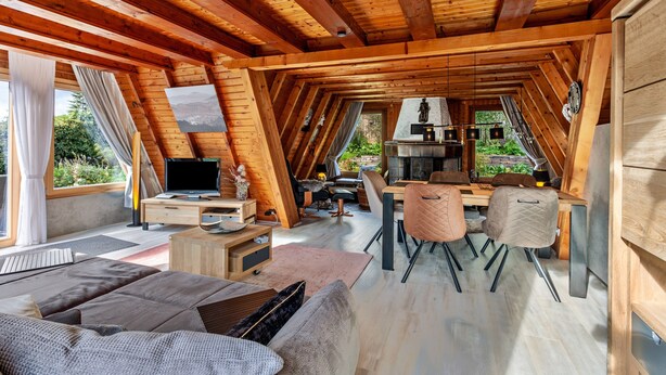 Un intérieur chaleureux et rustique, avec un espace repas, un téléviseur et un canapé.