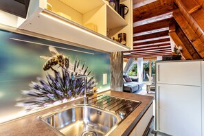 Una cocina moderna con un lavamanos de acero inoxidable, techo de madera y vista a una sala de estar acogedora.