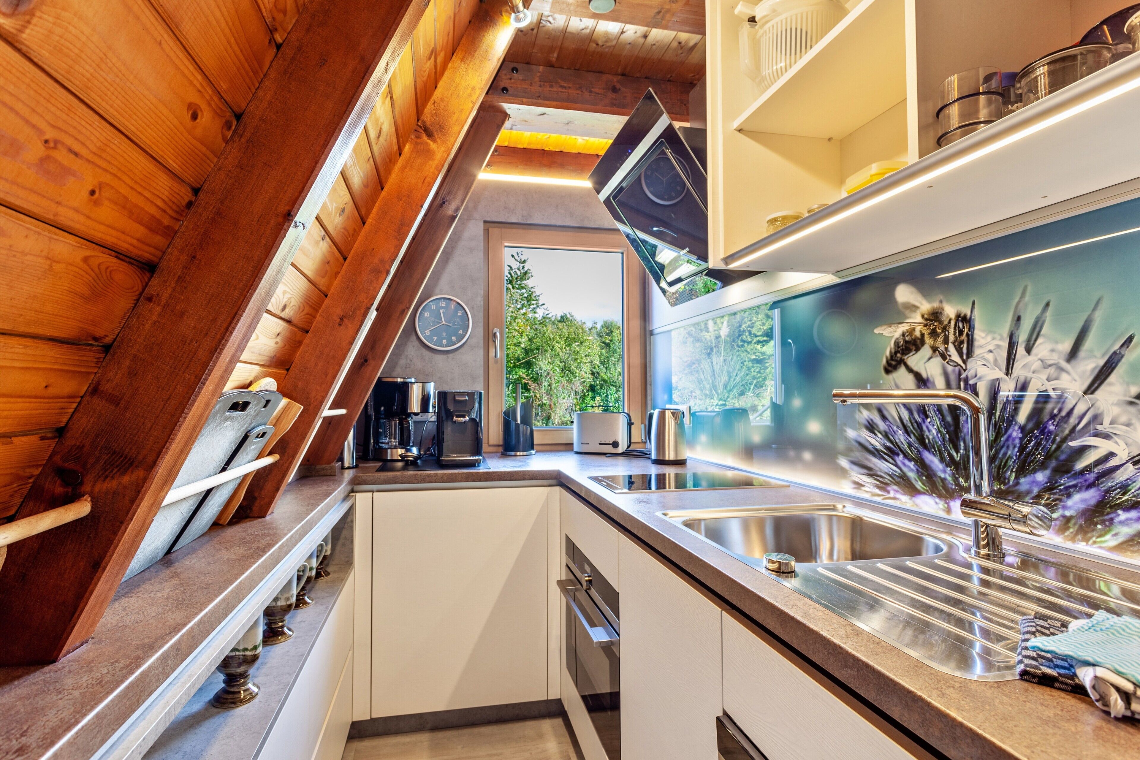 A kitchen with a modern design, featuring a stainless steel sink, a coffee maker, and a toaster.
