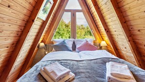 Une chambre avec un plafond en pente, une grande fenêtre et un lit avec des oreillers et des serviettes.