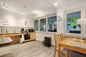 Una cocina moderna con comedor, armarios de madera, un microondas y un reloj en la pared.