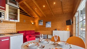 Ein gemütliches Blockhaus-Interieur mit Essplatz, einer roten Couch und Holzwänden.