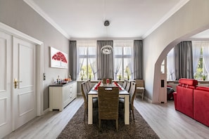 A dining area with a table set for four, a red sofa, and a red chair.