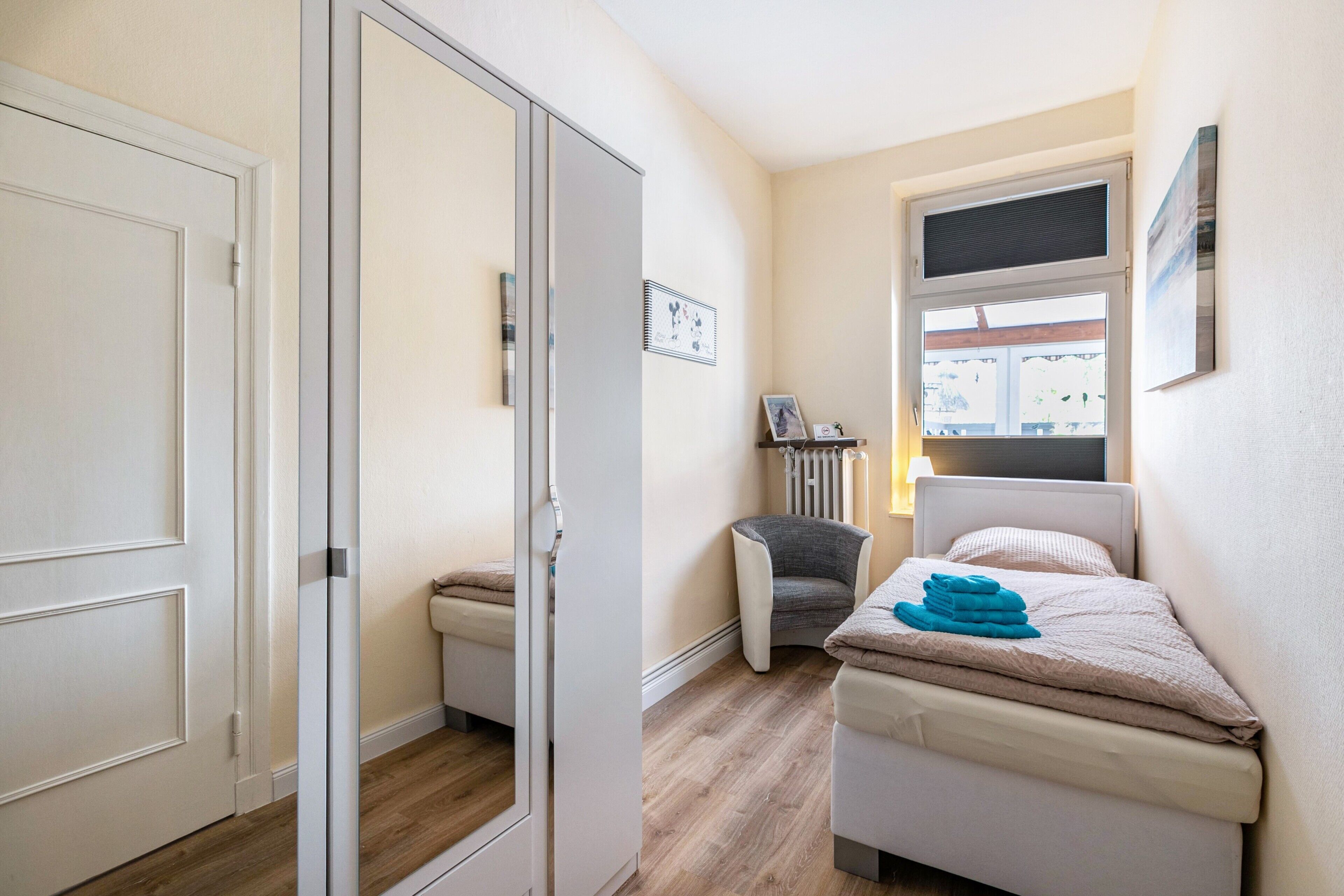 Ein Schlafzimmer mit einem Bett, einem Sessel, einem Heizkörper und einem Fenster.