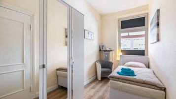Ein Schlafzimmer mit einem Bett, einem Sessel, einem Heizkörper und einem Fenster.