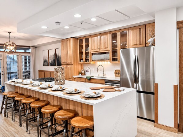 A modern kitchen with a central island, wooden cabinets, stainless steel appliances, and bar stools. - SKI IN/OUT- Pool table, hot tub, A+ kitchen, 7 bedrooms->4 kings+custom kid rms! (Snowshoe)