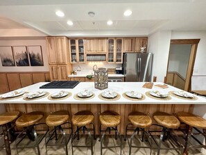 A modern kitchen with a central island, wooden bar stools, and a stainless steel refrigerator. - SKI IN/OUT- Pool table, hot tub, A+ kitchen, 7 bedrooms->4 kings+custom kid rms! (Snowshoe)