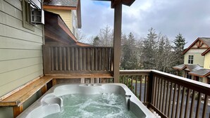 A hot tub on a wooden deck with a view of houses and trees in the background. - SKI IN/OUT- Pool table, hot tub, A+ kitchen, 7 bedrooms->4 kings+custom kid rms! (Snowshoe)